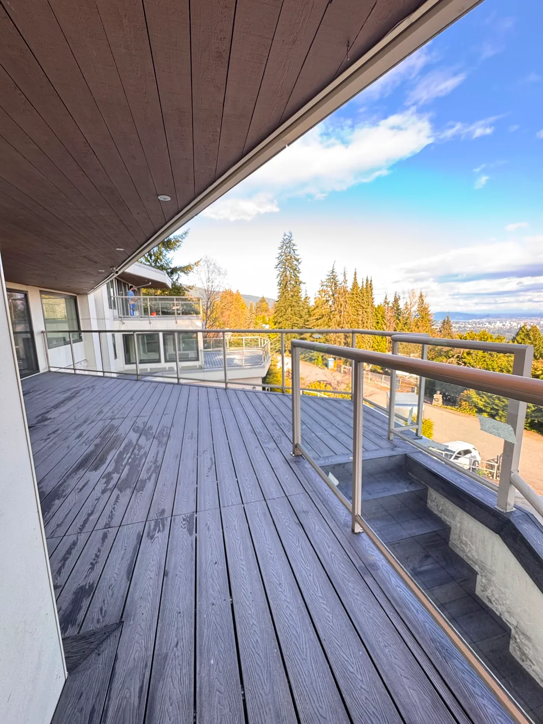 Grey composite deck with glass railing and mountain view
