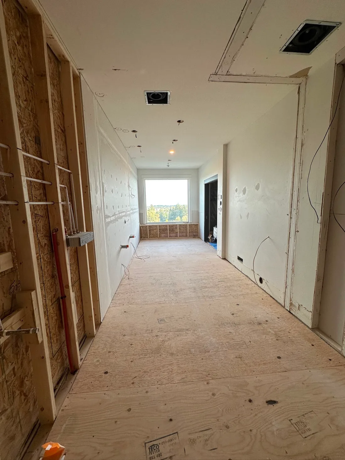 Interior hallway with framing, drywall, and ceiling preparation underway